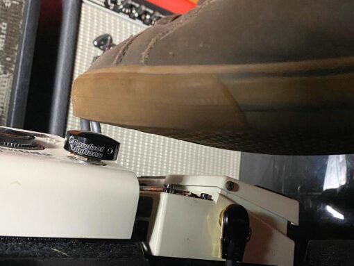 A shoe pressing a Barefoot Buttons V1 Standard Black footswitch topper installed on a guitar pedal.