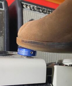 A shoe pressing a Barefoot Buttons V1 Standard Dark Blue footswitch topper installed on a guitar pedal.