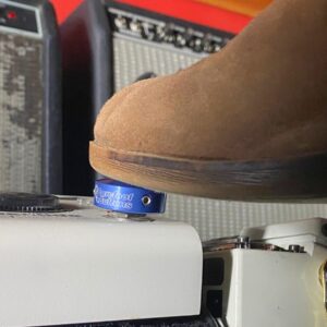 A shoe pressing a Barefoot Buttons V1 Standard Dark Blue footswitch topper installed on a guitar pedal.