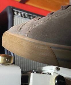 Close-up of a Barefoot Buttons V1 Standard Brass footswitch topper installed on a guitar pedal, pressed with a shoe.