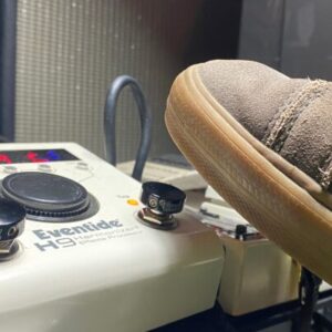 A V1 Mini Black Barefoot Buttton on an Eventide H9 pedal that is about to be stomped on by a shoe