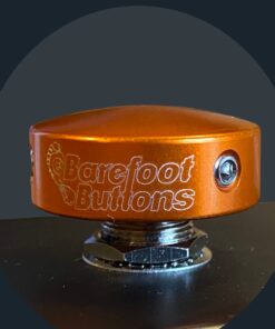 Orange Barefoot Button installed on a guitar pedal footswitch, showing secure fit and low-profile design.